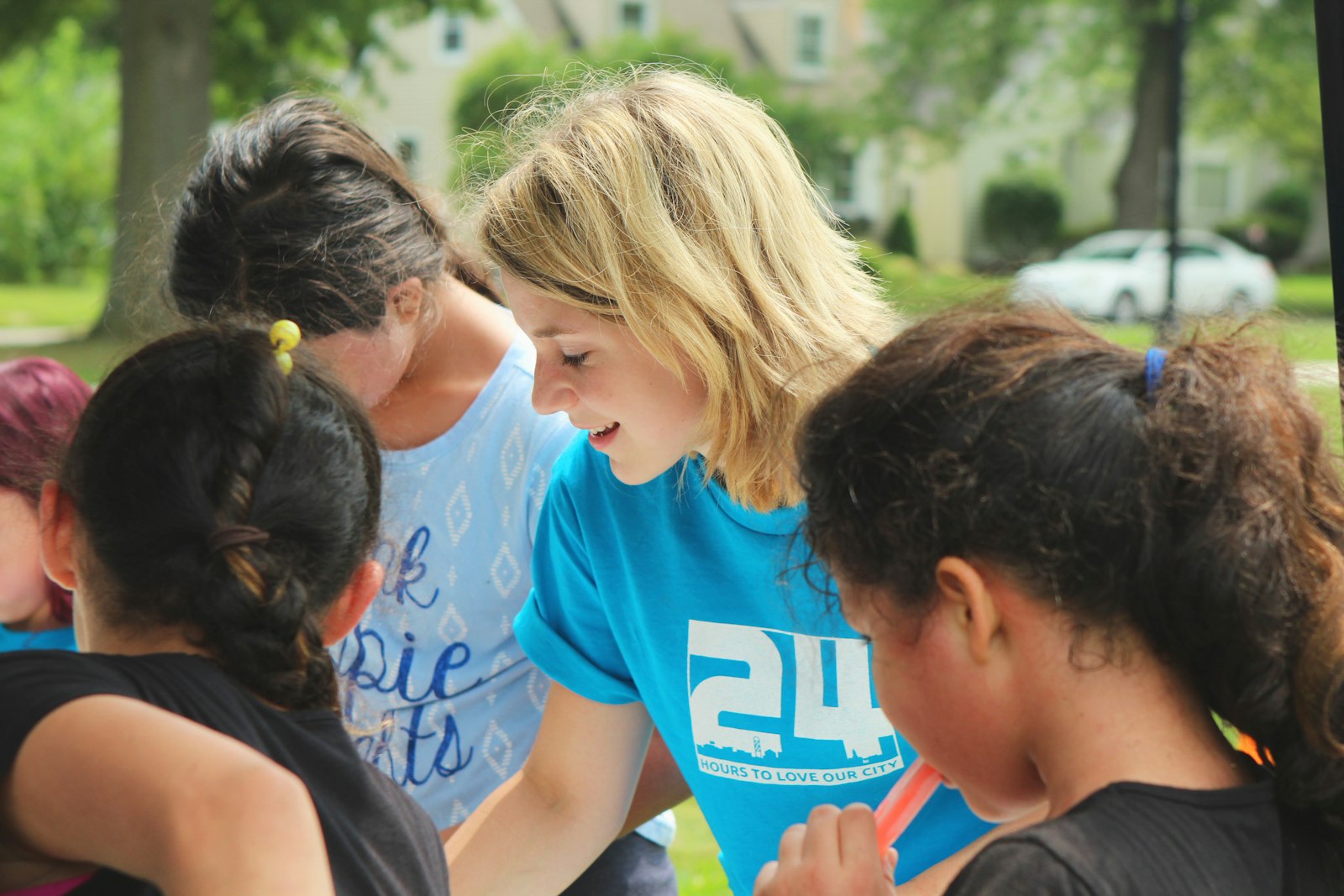 A volunteer sitting with a group of children, helping with schoolwork